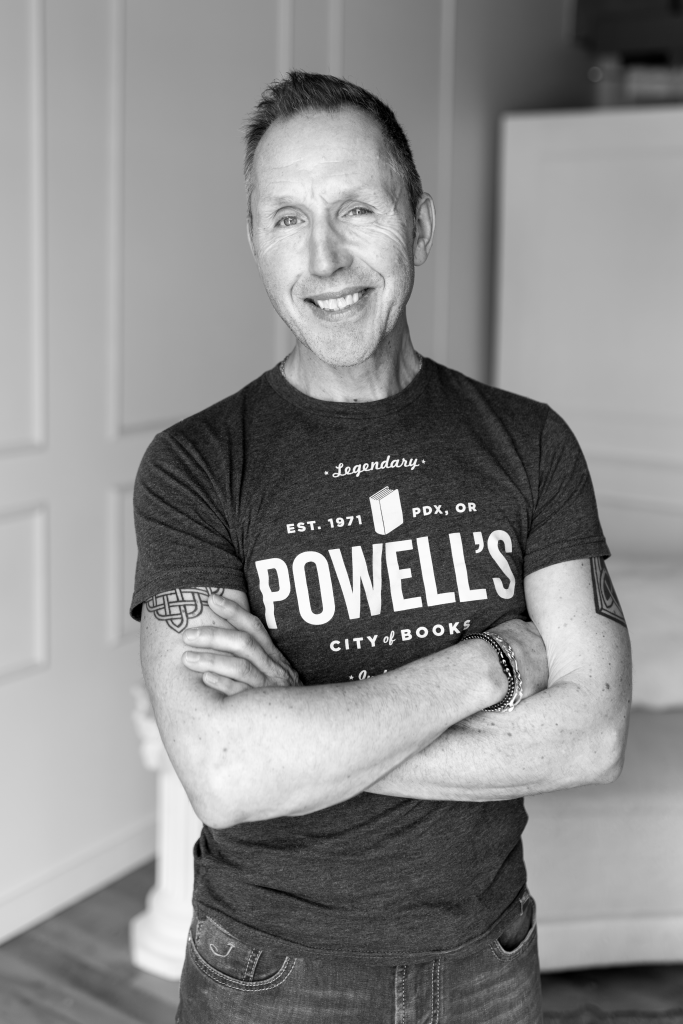 Tim Seefeldt smiling with his arms crossed. He is wearing a Powell's book store t-shirt.